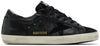 Golden Goose women’s Superstar sneaker with black leather upper, glitter heel tab, silver star, and distressed sole.